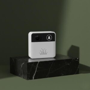 A hero product image of the white and black smart video doorbell sitting on a glossy black marble block. The background is a dark olive green wall with soft shadows, creating a sophisticated and aesthetic presentation.