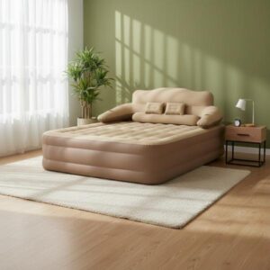 The tan inflatable bed with a built-in headboard and armrests is positioned in a modern, bright room on a light rug. The background features an olive green accent wall, and sunlight streams in from a window, casting shadows on the wall and floor, emphasizing its use as a temporary or permanent bed indoors.