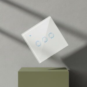 A white smart light switch levitating at a 45-degree angle above a dark olive green rectangular block. The background is a textured grey wall with sharp, diagonal shadows. The switch displays three blue illuminated touch controls and a Wi-Fi indicator, presented in a dynamic and artistic manner.