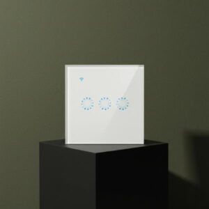 A hero shot of a white smart light switch standing upright on a matte black cubic block. The background is a dark olive green wall with soft shadows, creating an aesthetic and refined presentation. The switch features three circular blue illuminated touch controls and a blue Wi-Fi indicator at the top right.