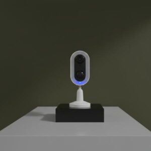 The camera is on a black rectangular block, on a white table, with a slightly darker olive green background