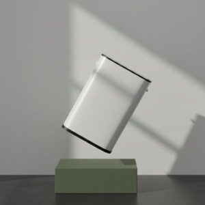 A white rectangular smart bin is shown levitating above a matte olive green rectangular block. The bin is tilted at an angle. The background is a light grey wall with strong shadows cast from a directional light source, creating a dramatic, minimalist presentation.
