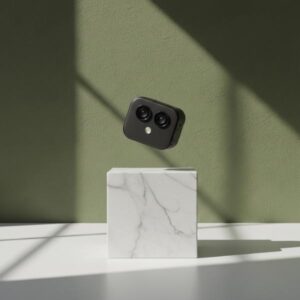 A black mini camera levitating/floating mid-air above a white marble block, with an olive green background wall and soft shadows.