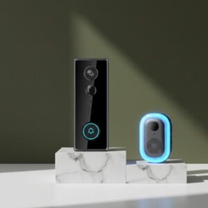 A black doorbell unit and its small, blue-glowing chime unit are standing side-by-side on a white marble block with soft black veins. The background is olive green with soft shadows.