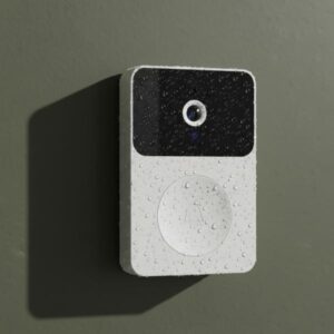 A close-up of the white smart doorbell unit, which appears to have water droplets on its surface, installed on a matte olive green wall.
