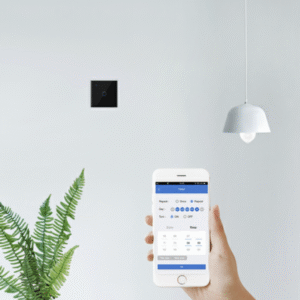 A hand holding a smartphone displaying the timer function interface of a smart home app, showing options for repeat, once, turn on/off, date, and time settings. In the background, a black smart touch switch is mounted on a white wall near a potted fern and a modern pendant light, illustrating convenient digital control.