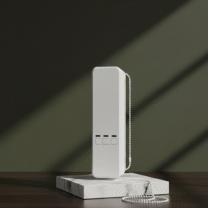 A tall, slender white smart curtain or blind motor standing upright on a white marble block, with a power cord coiled at its base. The background is a textured olive-green wall.