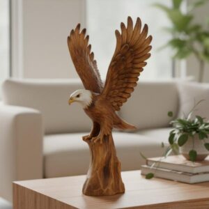 A hand-carved wooden eagle statue placed on a light wooden coffee table in a modern living room setting, with a white sofa and green plants visible in the softly lit background.
