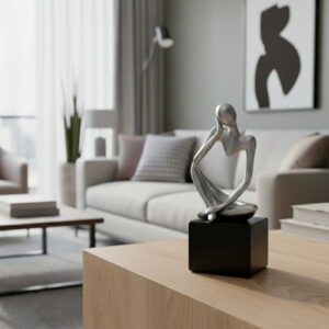 Silver Thinking Man sculpture placed on a wooden coffee table in a modern, brightly lit living room setting.