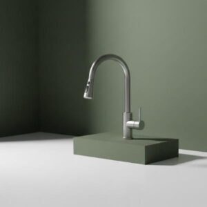 Brushed silver kitchen faucet resting on a matte olive green rectangular plinth, on a white countertop with an olive green wall background.